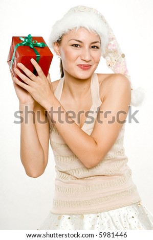 A young attractive woman in santa hat and skirt trying to find out what\'s in the gift