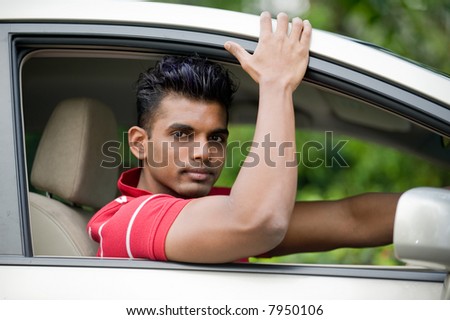 A well-built Asian man in a saloon car in the country