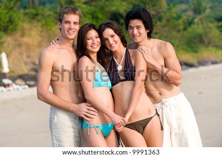 Four friends standing together on a tropical beach