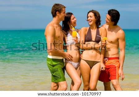 Four young adults standing by ocean with drinks