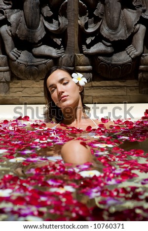 A young woman in a bath with petals and flowers