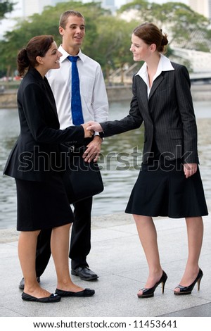 Three business executives meeting and greeting by a river in the City