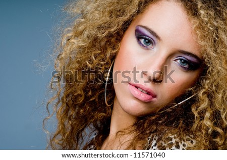 A young beautiful woman with great curly hair in animal print dress on grey background