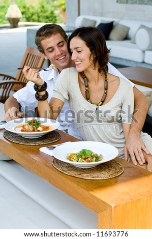 A young couple on vacation eating lunch at a relaxed outdoor restaurant