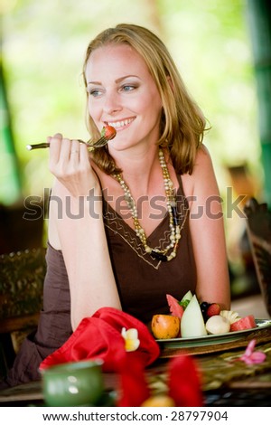 An attractive woman eating a healthy breakfast of fruit