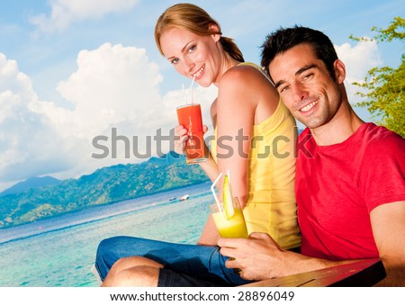 A young couple on vacation enjoying drinks with a sea view