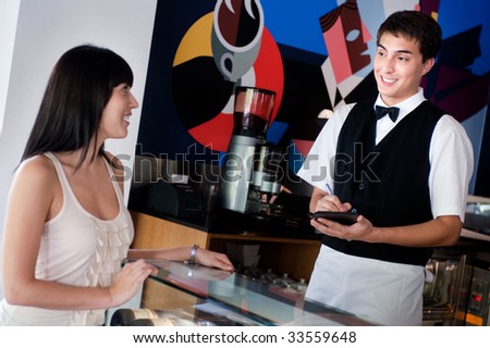 A young and attractive waiter taking an order from a customer in an indoor restaurant