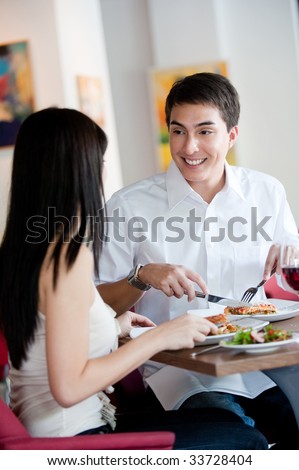 A young and attractive man dining with his partner in an indoor restaurant