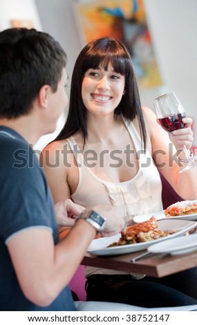A young and attractive woman dining with her partner in an indoor restaurant