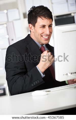 An attractive businessman receives good news online at his office