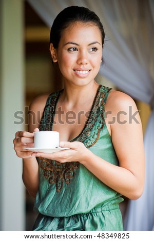 An attractive young woman having a drink and relaxing indoors