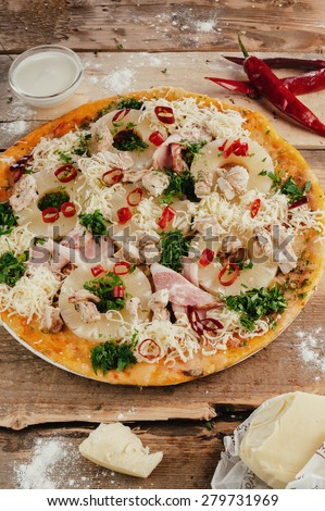 Styled pizza with vegetables and meat on wooden table