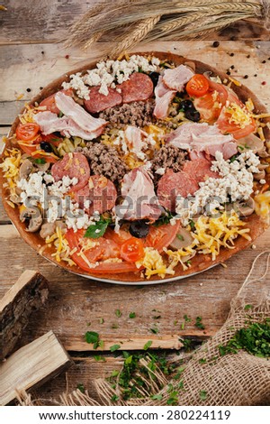 Pizza with sausage and meat on wooden table. Vertical top view
