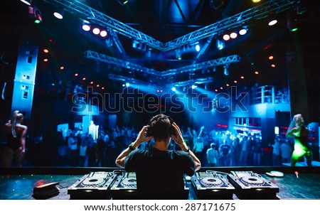 DJ with headphones at night club party under the blue light and people crowd in background Сток-фото © 