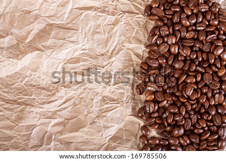 the fried beans of coffee on a crushed paper  background