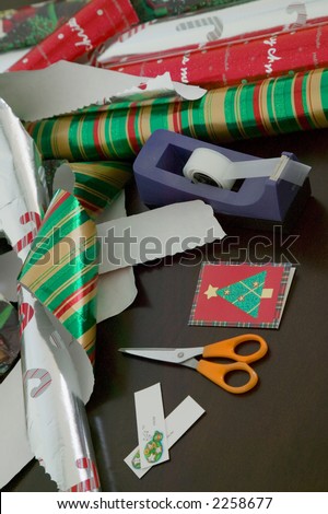 Rolls of christmas wrapping paper with scissors, note tags and sticky tape