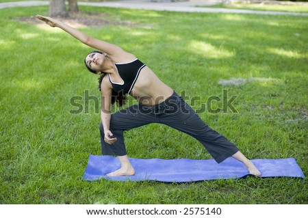 A sexy young hispanic woman in black sports outfit  practices Yoga at the park