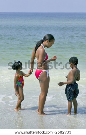 African american mother and two children enjoy a day relaxing and playing at the beach