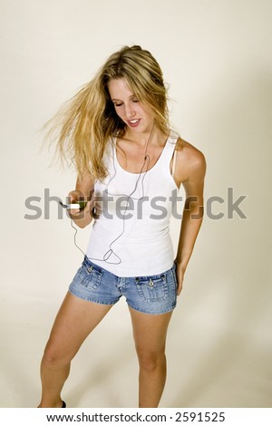 young attractive blond woman in white tee shirt and denim jeans listens to music on her MP3 player