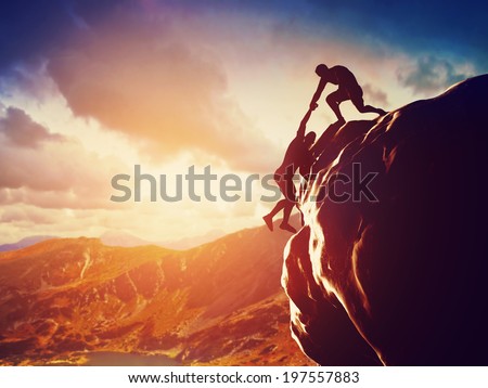 Hikers climbing on rock, mountain at sunset, one of them giving hand and helping to climb. Help, support, assistance in a dangerous situation 商業照片 © 