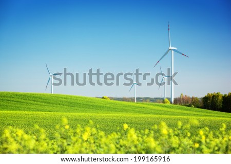 Wind turbines on spring field. Alternative, clean and natural source of energy is gaining pupularity. Eco farm.