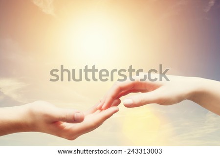 Soft, gentle touch of man and woman against sunny sky with flare in vintage mood. Love, connection, help concepts.