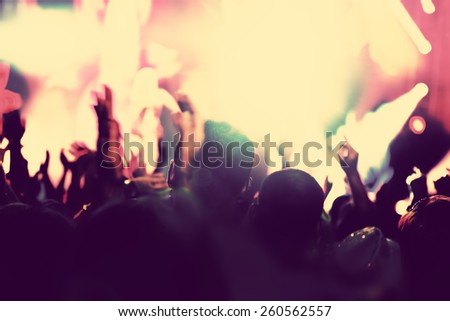Concert, disco party. People with hands up having fun in night club lights. Vintage mood