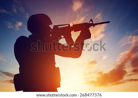 Soldier shooting with his weapon, rifle at sunset. War, army, military.
