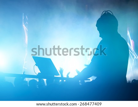 Club, disco DJ playing and mixing music for crowd of happy people. Nightlife, concert lights, flares