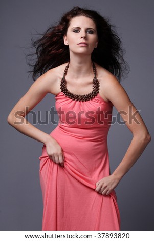 Young fashion model with long curly hair in pink dress.
