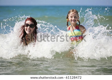 Young mother and daughter enjoy hot summer day in the water.