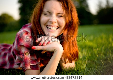 Young happy woman relaxing on green grass.
