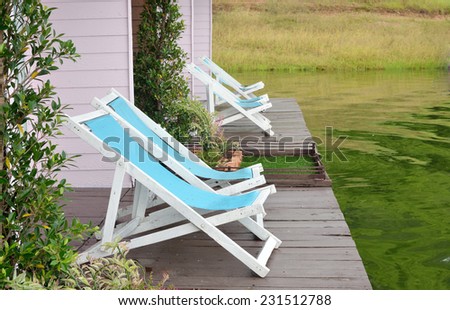 Two Recline chairs on dock facing a green lake.