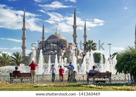 Tourists admiring the view of the fountain and Blue Mosque (Sultanahmet Camii) in Istanbul, Turkey