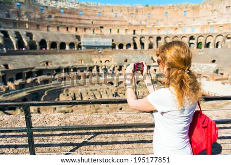 ROME - MAY 1O: Young female tourist takes a picture inside the Coliseum on may 10, 2014 in Rome. The Colosseum is an important monument of antiquity and is one of the main tourist attractions of Rome.