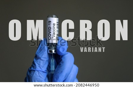 Omicron COVID-19 variant poster, coronavirus vaccine bottle and syringe in doctor gloved hands. Concept of COVID19 vaccination, corona virus mutation, danger and vaccine injection during pandemic.