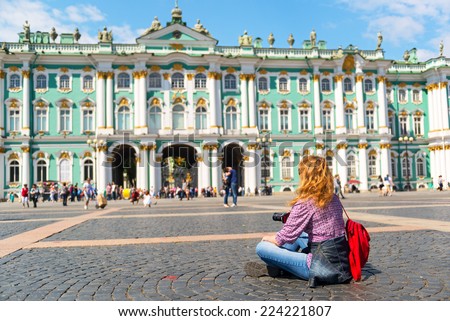 Young female tourist resting on the square in front of the Winter Palace in St. Petersburg, Russia