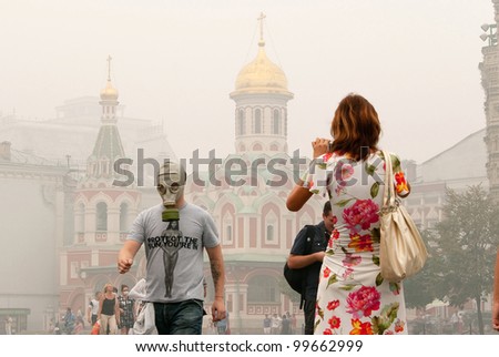 MOSCOW - AUGUST 7, 2010: Tourists in a gas mask to protect from the high concentration of carbon monoxide caused by smoke from the forest fires on the Red Square on august 7, 2010 in Moscow, Russia.