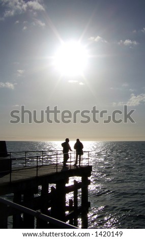 Two peaceful people talk silhouetted against a gleaming ocean
