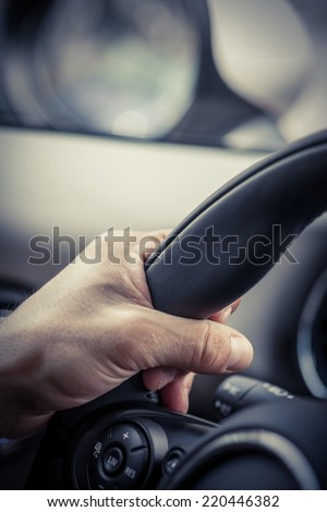 A hand pushes the cruise control button on a steering wheel.
