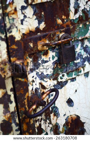 Color picture of a rusty padlock on a rusty metal door.