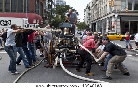 NEW YORK - SEPTEMBER 22: Team working on antique hand-pumped fire truck during Fire museum family day competing on distance water pumping on September 22, 2012 in New York City