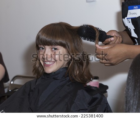 New York, NY - October 18, 2014: Girl prepares backstage for PetiteParade Kids Fashion week at Bath House Studios