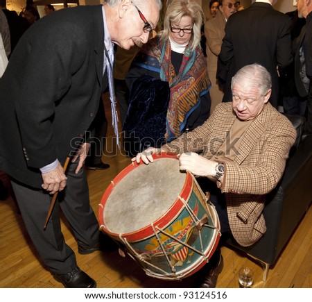 NEW YORK - JANUARY 18: Unidentified buyer examines antique drum at opening night of inaugural NYC Metro Show at Metropolitan Pavilion on January 18, 2012 in New York City, NY