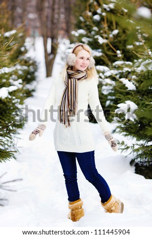 Smiling young girl walking in winter forest, a full-length portrait, vertical photo, look away
