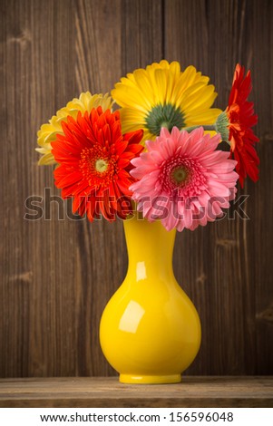 Gerbera flower on the vase, and the wooden background.