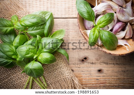 Bunch fresh basil on a wooden background. Garlic mixture in a bowl.