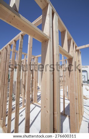 New construction home framing against a blue sky and sun