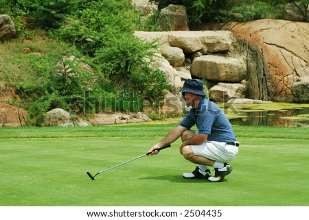 Middle age golfer estimating the line for the putt on South African golf course.