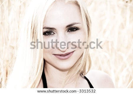 Portrait of a blonde woman with green eyes smiling, on a sunny day.